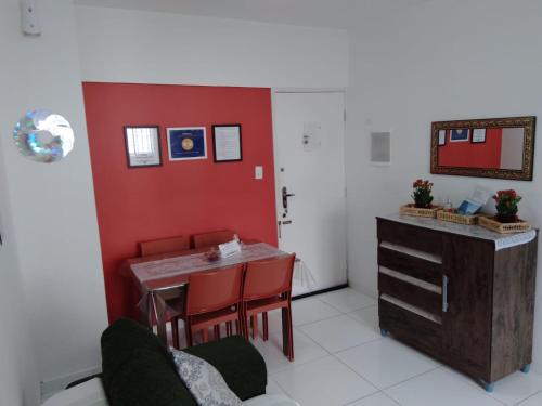 ein Esszimmer mit einem Tisch und einer roten Wand in der Unterkunft Lindo studio na Praia do Gonzaguinha in São Vicente