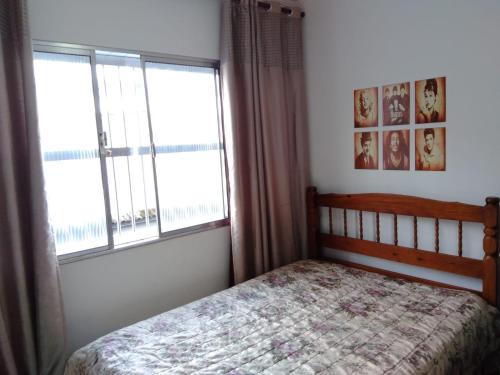 ein Schlafzimmer mit einem Bett und zwei Fenstern in der Unterkunft Lindo studio na Praia do Gonzaguinha in São Vicente