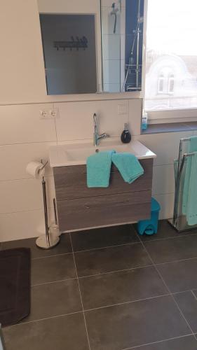 ein Bad mit einem Waschbecken, einem Spiegel und blauen Handtüchern in der Unterkunft Charakterhaus in Neulengbach