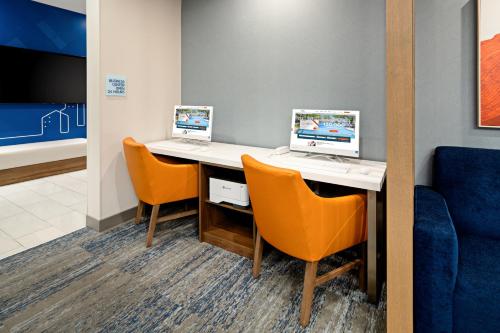 two computers sitting on a desk with orange chairs at Holiday Inn Express & Suites Palm Desert - Millennium by IHG in Palm Desert