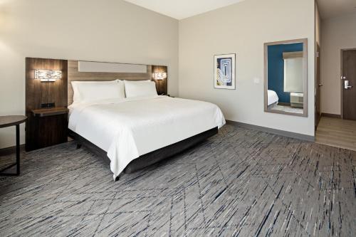 Holiday Inn Express & Suites Palm Desert - Millennium, an IHG Hotel في بالم ديزرت: غرفة الفندق بسرير كبير ومرآة