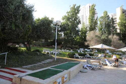 エルサレムにあるJerusalem Hotel Private Luxury Suites near Western Wallのラウンジチェア、パラソル、テーブルが備わる公園