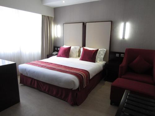 a hotel room with a large bed and a red chair at The Zehneria Hotel in Nairobi