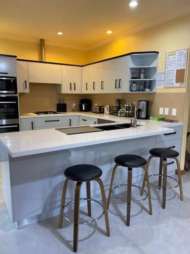 a kitchen with a large white counter with two bar stools at Abel Tasman Marahau in Marahau