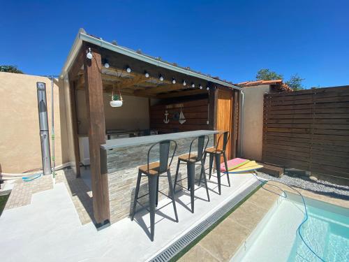 un patio avec un bar avec des chaises à côté d'une piscine dans l'établissement Jolie Villa climatisée piscine parking Perpignan, à Perpignan