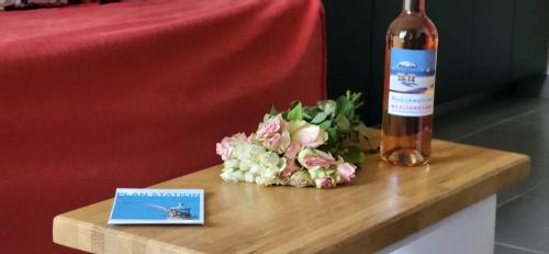 une bouteille de vin et une composition florale sur une table dans l'établissement La Caravelle entre Plage et Centre Ville, au Grau-du-Roi