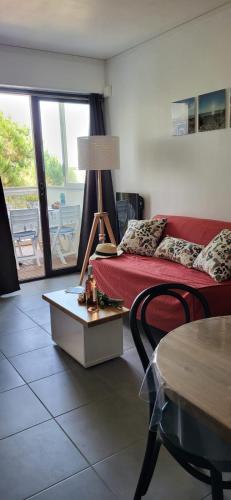 un salon avec un canapé rouge et une table dans l'établissement La Caravelle entre Plage et Centre Ville, au Grau-du-Roi