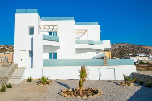 a white house with a palm tree in front of it at Thalasidi Luxury Suites in Karpathos Town