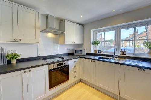 a kitchen with white cabinets and a sink and a window at Kist Accommodates - Duck Hill Cottage in Ripon