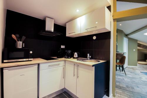 une cuisine avec des armoires blanches et un évier dans l'établissement La Forêt, T2 hypercentre chic et cosy, Wifi par SOVALFI, à Saint-Étienne