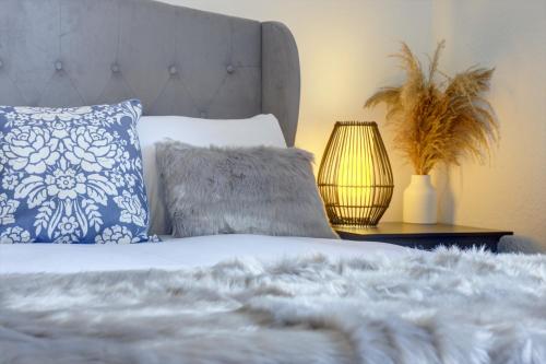 a bed with blue and white pillows and a lamp at Kist Accommodates - Duck Hill Cottage in Ripon