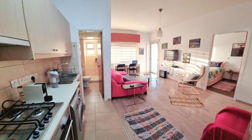 a large kitchen and living room with a pink chair at ARTEMIS 3, Beachfront Boutique Apartment in Limassol