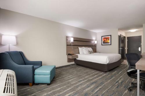 une chambre d'hôtel avec un lit et une chaise bleue dans l'établissement Best Western NSU Inn, à Tahlequah