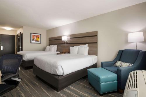 a hotel room with two beds and a blue chair at Best Western NSU Inn in Tahlequah
