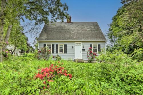 a small white house in a field of flowers at Walk to Beach and Main Street Hyannis Cottage in Barnstable
