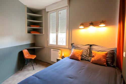 - une chambre avec un lit doté d'oreillers orange et une fenêtre dans l'établissement Le Victorien, T2 hypercentre chic et cosy, Wifi par SOVALFI, à Saint-Étienne