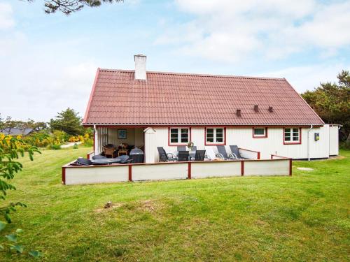 uma casa branca com um telhado vermelho num quintal em 7 person holiday home in Ulfborg em Fjand Gårde