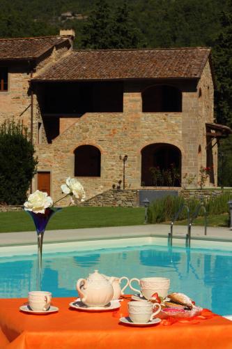 a table with cups and saucers on it next to a pool at Tenuta Poggio Marino in Dicomano
