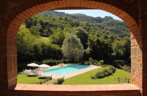 uma vista para uma piscina através de um arco em Tenuta Poggio Marino em Dicomano