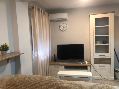 sala de estar con TV en una mesa y reloj en Urban - Apartamento céntrico en Alcalá de Henares, en Alcalá de Henares