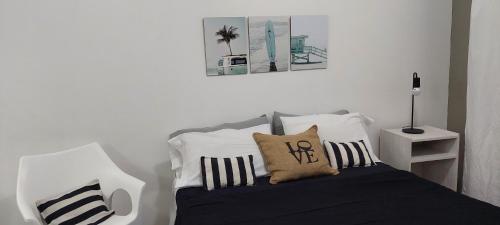 1 dormitorio con 1 cama con almohadas blancas y negras en Monoambiente Manquel en Necochea