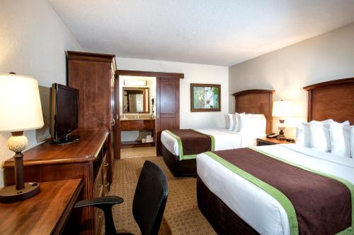 um quarto de hotel com duas camas e uma secretária e uma televisão em Rosen Inn Lake Buena Vista em Orlando