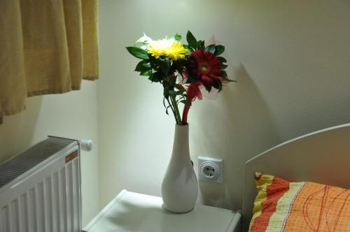 a white vase with flowers in it on a table at Rooms Turist in Vladičin Han
