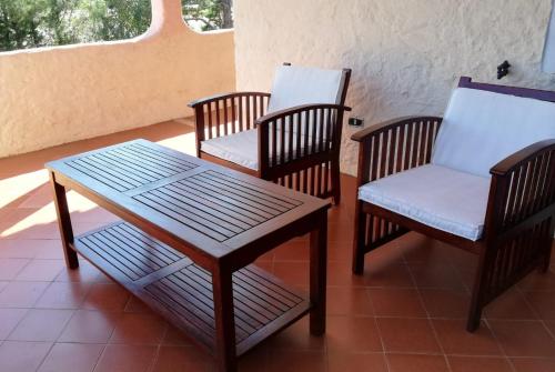 a porch with three chairs and a table and a table and chairs at La Cuppulata in Budoni