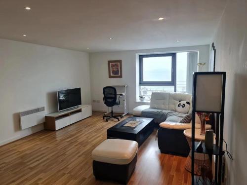 a living room with a couch and a tv at Stunning Waterfront Western harbour Apartment in Edinburgh