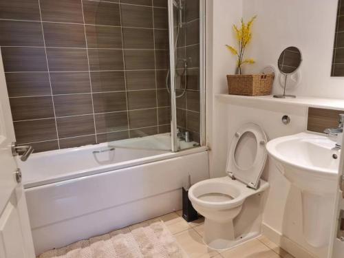 a bathroom with a toilet and a tub and a sink at Stunning Waterfront Western harbour Apartment in Edinburgh