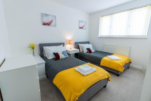 a bedroom with two beds with yellow blankets at 4 en-suite bedroom house with free parking Aylesbury in Buckinghamshire