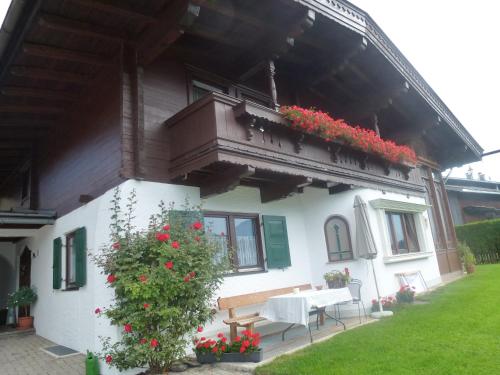 a house with a porch with a bench and flowers at Gästehaus Rosi in Fieberbrunn