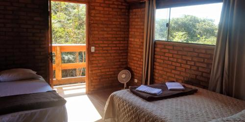 een slaapkamer met een bed en een raam met een ventilator bij Chalé 2 Recanto Shambala - a 2,5 km de São Thomé in São Thomé das Letras