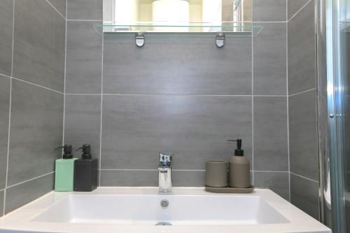 - un lavabo dans la salle de bains avec 2 bouteilles dans l'établissement Le Vintage, T2 hypercentre chic et cosy, Wifi par SOVALFI, à Saint-Étienne
