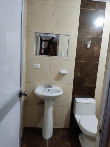 a bathroom with a toilet and a sink and a mirror at D' Barrig in Trujillo