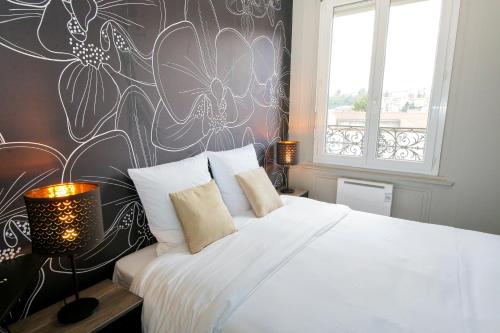 - une chambre avec un lit blanc et un mur fleuri dans l'établissement Le Vintage, T2 hypercentre chic et cosy, Wifi par SOVALFI, à Saint-Étienne
