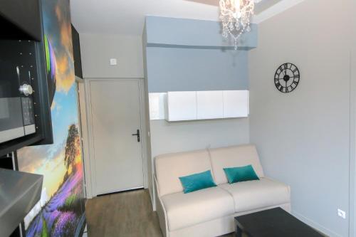 - un salon avec un canapé blanc et 2 oreillers bleus dans l'établissement Le Vintage, T2 hypercentre chic et cosy, Wifi par SOVALFI, à Saint-Étienne