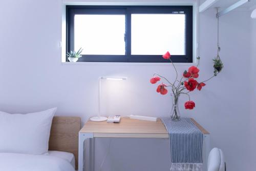 a vase with red flowers on a table in a bedroom at japan house sugamo in Tokyo