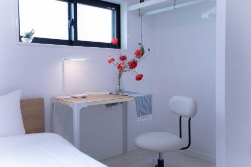 a bedroom with a desk with a vase of flowers and a chair at japan house sugamo in Tokyo