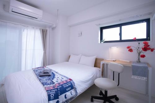 a white bedroom with a bed and a chair at japan house sugamo in Tokyo