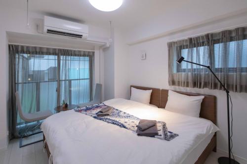 a bedroom with a white bed with a lamp and windows at japan house sugamo in Tokyo