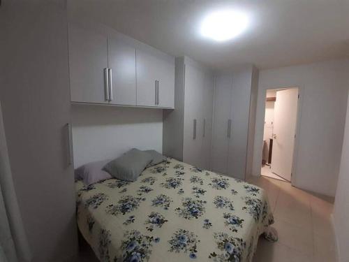 1 dormitorio con 1 cama con edredón de flores en Apartamento Padrão em condominio completo no Recreio en Río de Janeiro