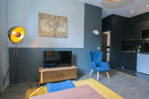 un salon avec des chaises bleues et une télévision dans l'établissement L'Eléphant, T2 hypercentre chic et cosy, Wifi par SOVALFI, à Saint-Étienne