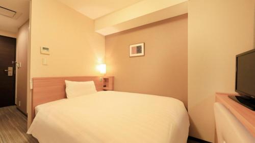 a bedroom with a white bed and a television at Via Inn Shinagawa Oimachi in Tokyo