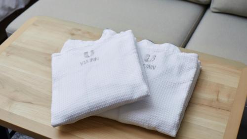 two white towels sitting on a wooden table at Via Inn Shinagawa Oimachi in Tokyo