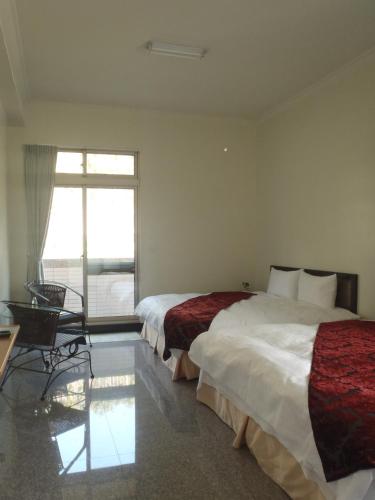 a hotel room with two beds and a window at De Ren Tea Gardens in Meishan