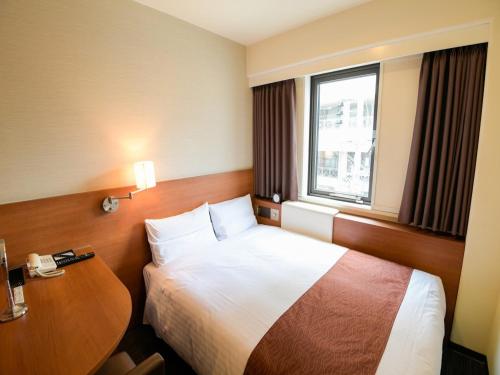 大阪市にあるヴィアイン新大阪ウエスト (JR西日本グループ)のベッドとテーブルが備わるホテルルームです。