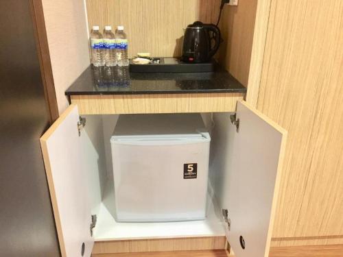 a cupboard with a sink and bottles of water at Hotel Holmes Gp in Nusajaya