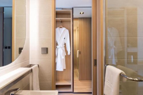 y baño con ducha y albornoz blanco. en Connect Busan Hotel & Residence en Busan