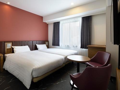2 camas en una habitación de hotel con mesa y sillas en Via Inn Shinsaibashi, en Osaka